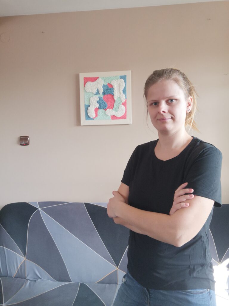 artystka na obrazie za plecami na ścianie nad sofą obraz