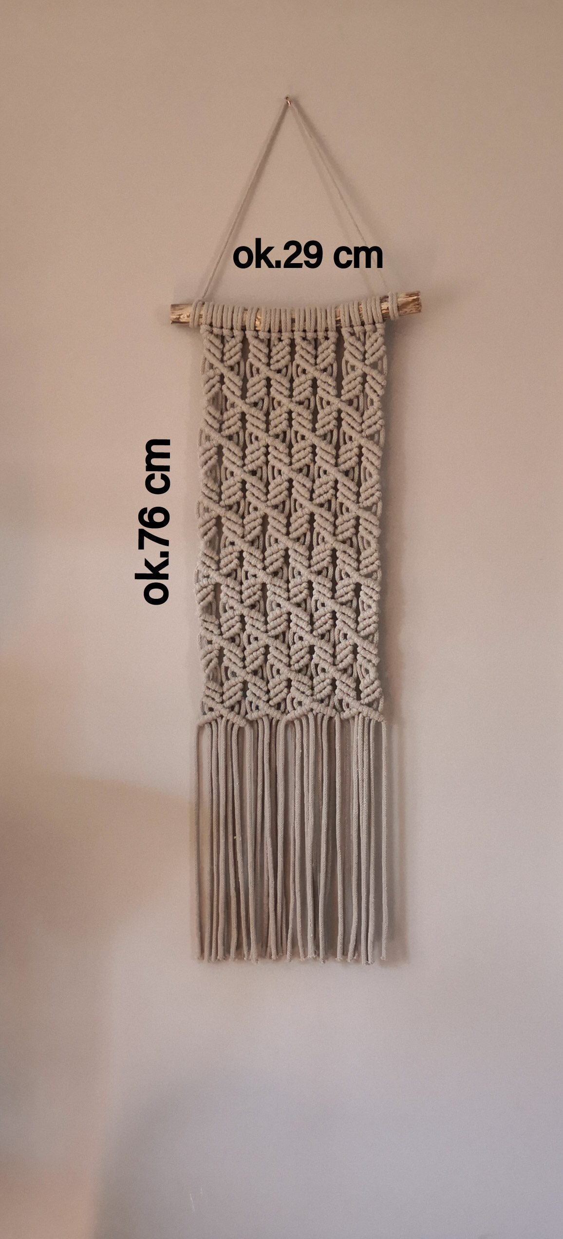 Ręcznie robiona makrama ścienna w jasnym brązowym kolorze, z geometrycznym wzorem plecionym ze sznurka bawełnianego. Makrama o długości ok. 76 cm i szerokości ok 29 cm.